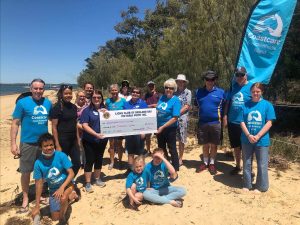 Coochiemudlo Coast Care volunteers on the beachcelebrate the receipt of funding from RedVic Lions