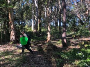 Tali Shelley of Bushtekniq carrying a basket of pulled weeds in the bush.