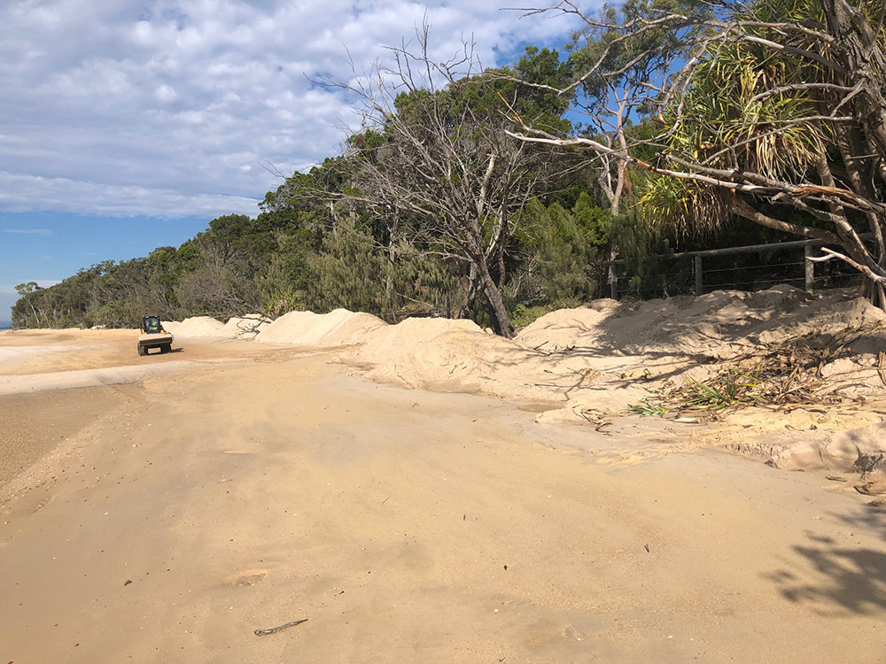 A skid steer on Morwong Beach working to distribute loads of sand on the sand replensihment project, June 2023.